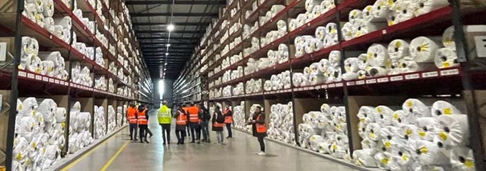Grupo Nacional Intercésped Almacén con rollos de césped artificial y grupo de visitantes