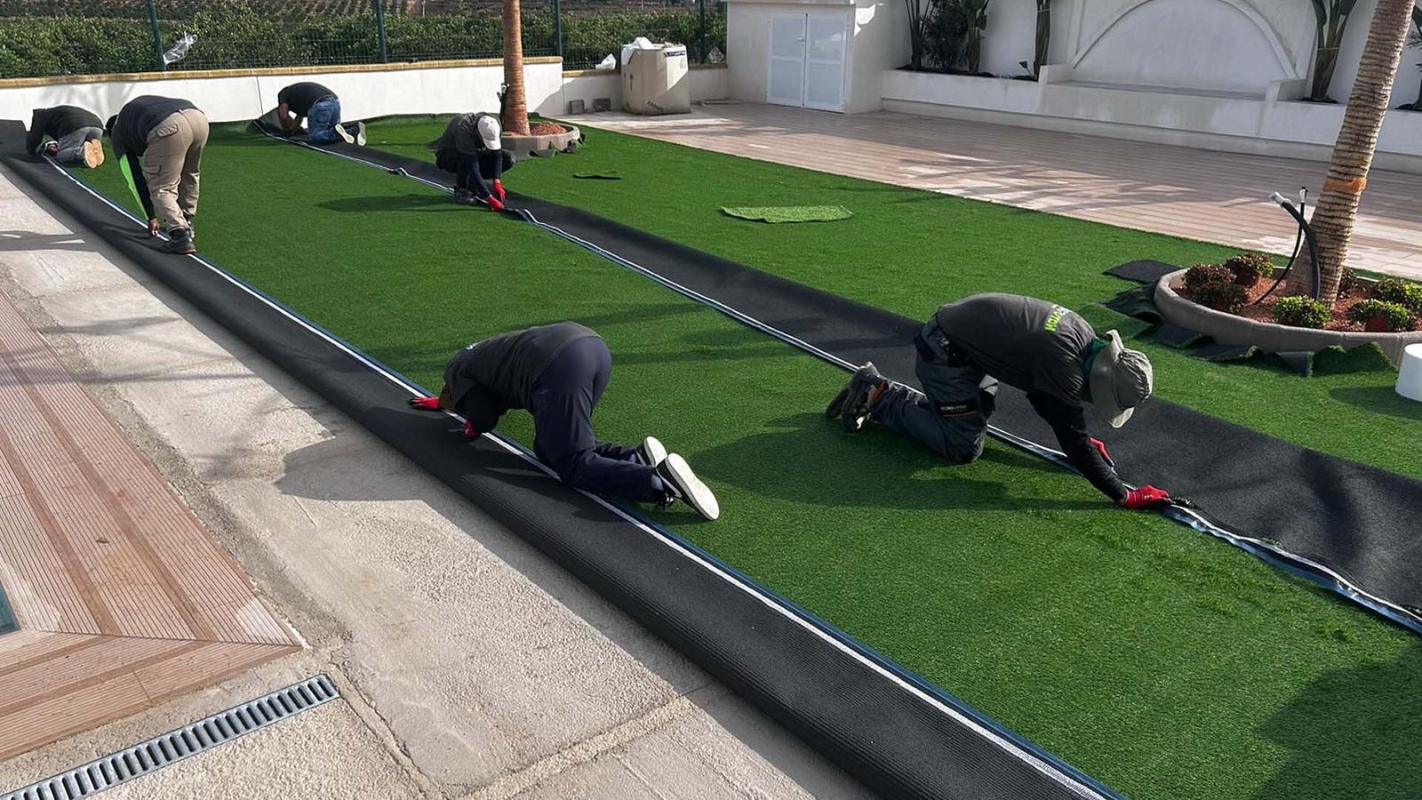 Equipo de instaladores ajustando los paños de césped artificial