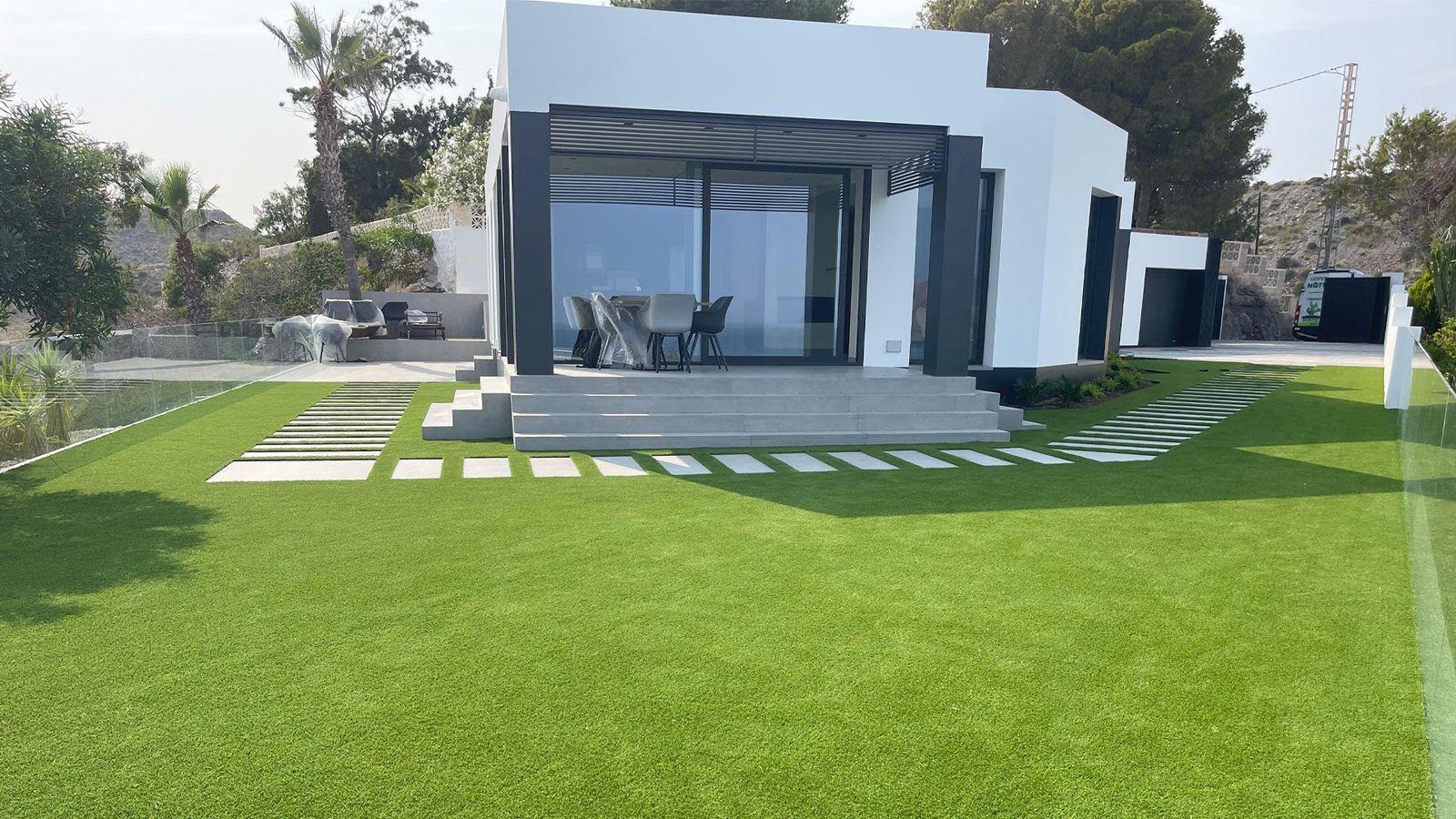 Jardín con césped artificial junto a una vivienda
