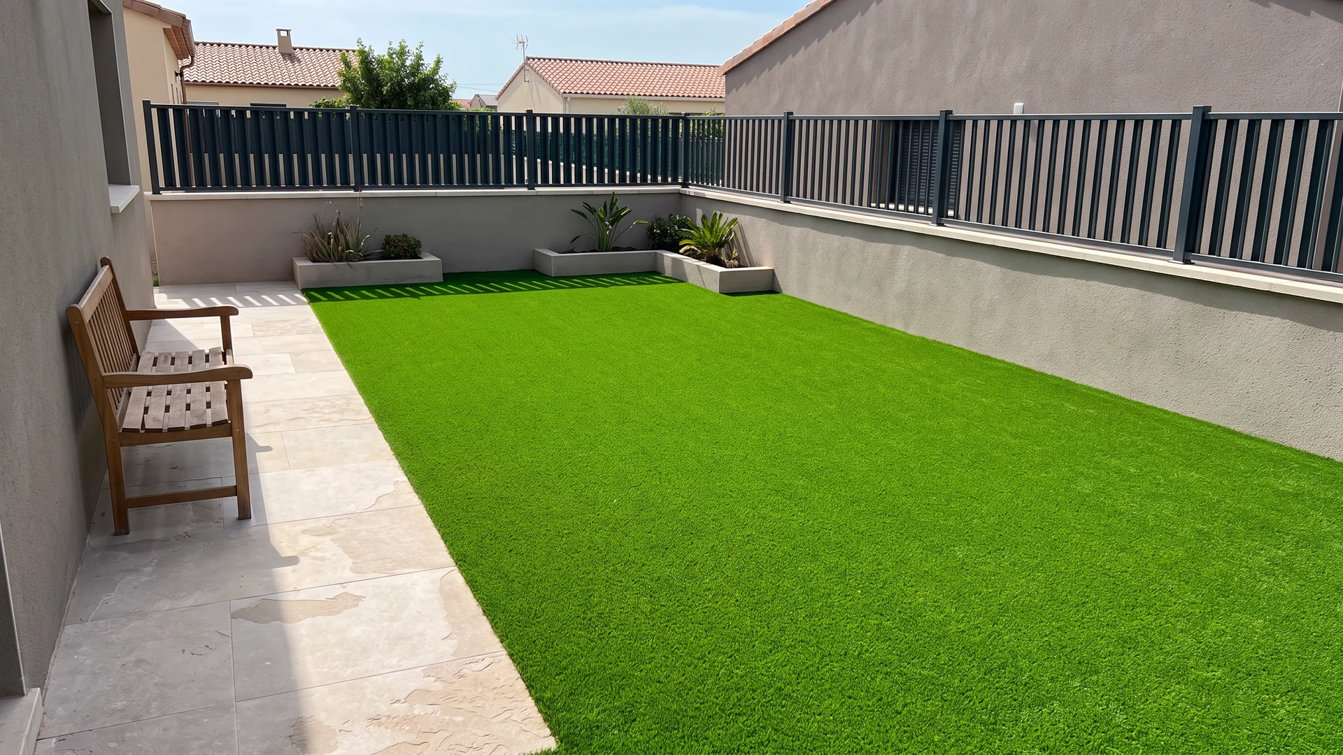 Terraza con césped artificial, banco y jardineras junto a una barandilla Terraza con césped artificial, banco y jardineras junto a una barandilla.