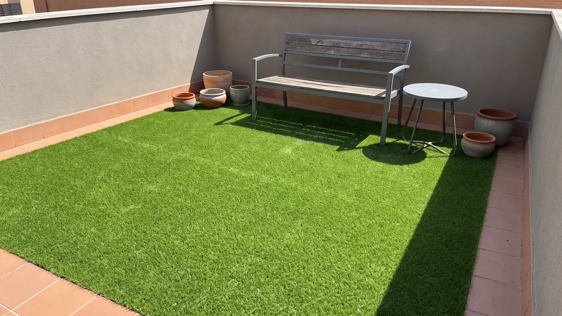 Patio con césped artificial, banco, mesa auxiliar y macetas Patio con césped artificial, banco, mesa auxiliar y macetas.