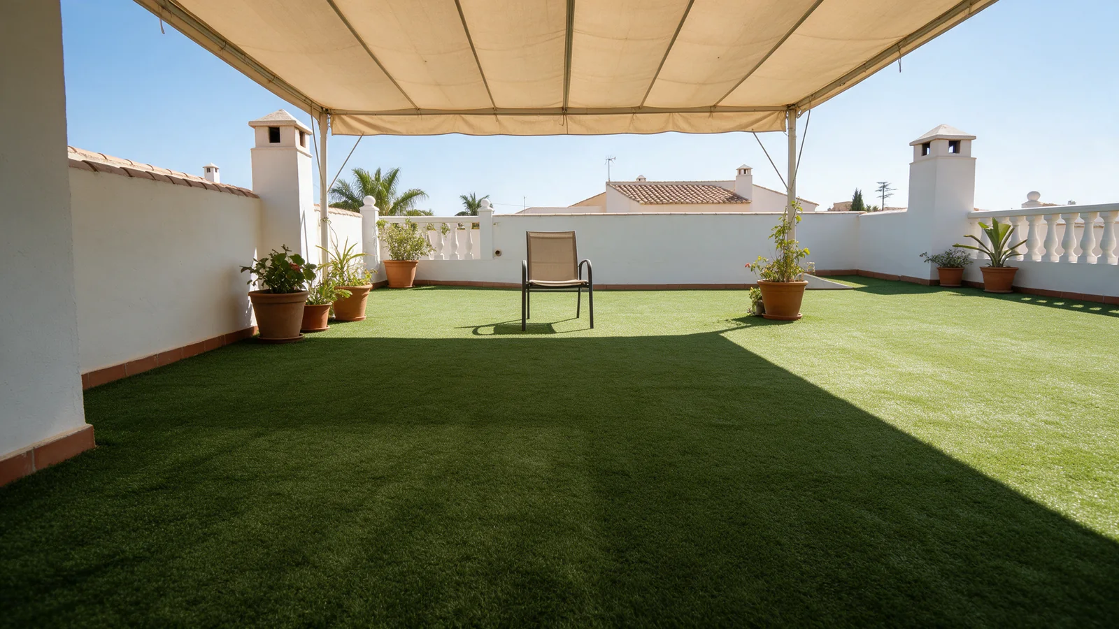 Terraza de césped artificial con una zona sombreada por un toldo.