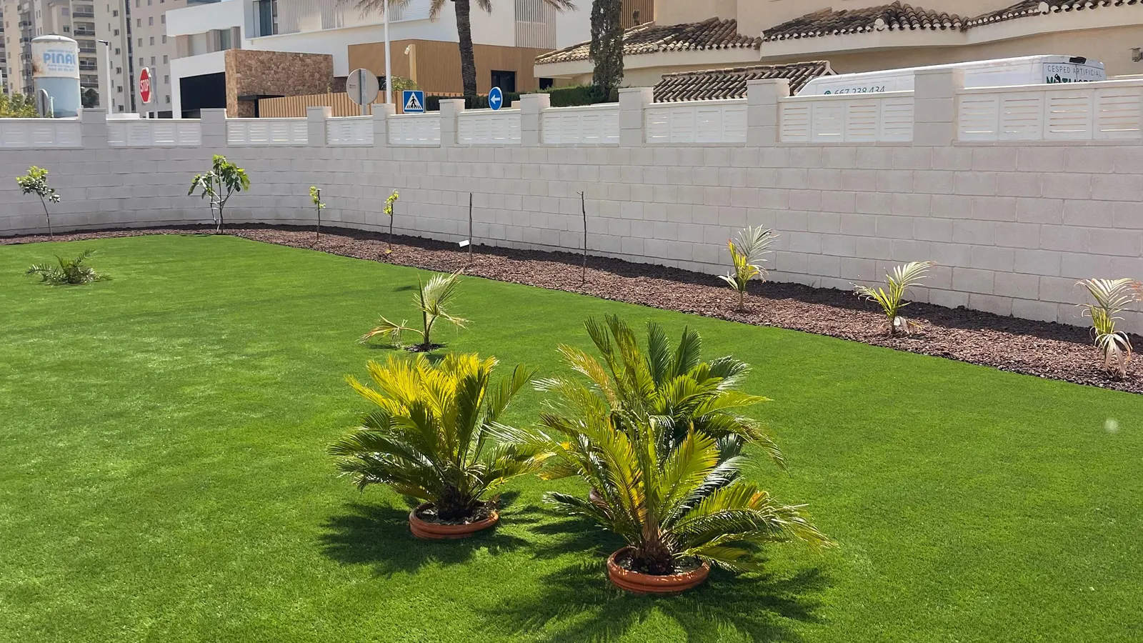 Césped artificial en jardín, parterre junto a muro perimetral