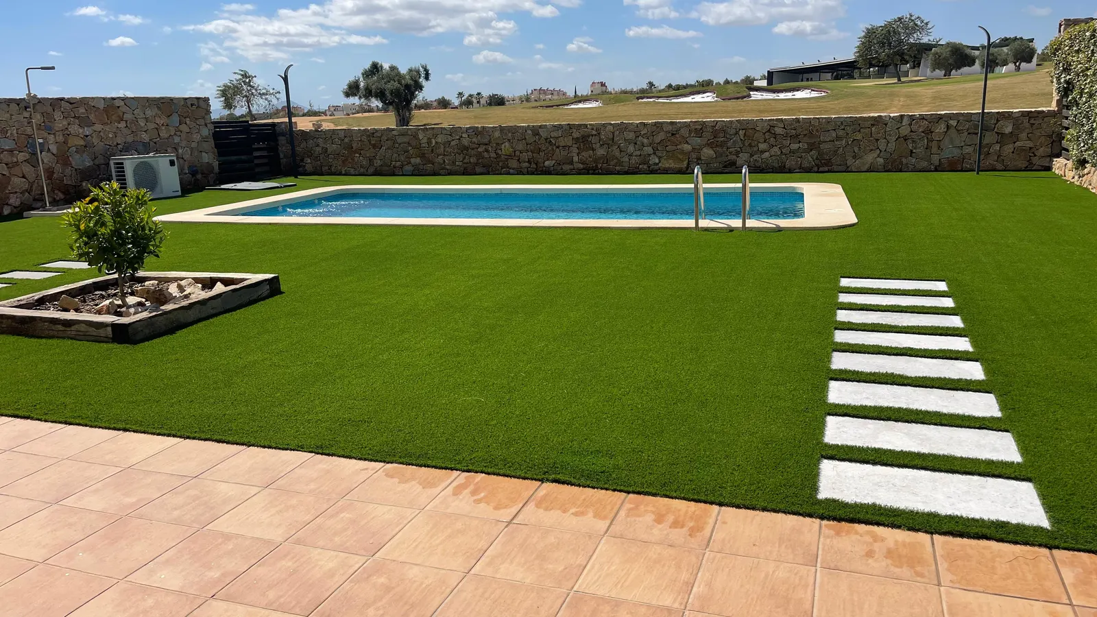 Césped artificial en piscina, piscina rectangular y sendero de losas